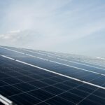 Rows of solar panels are installed outdoors under a clear sky, capturing sunlight and generating renewable energy.