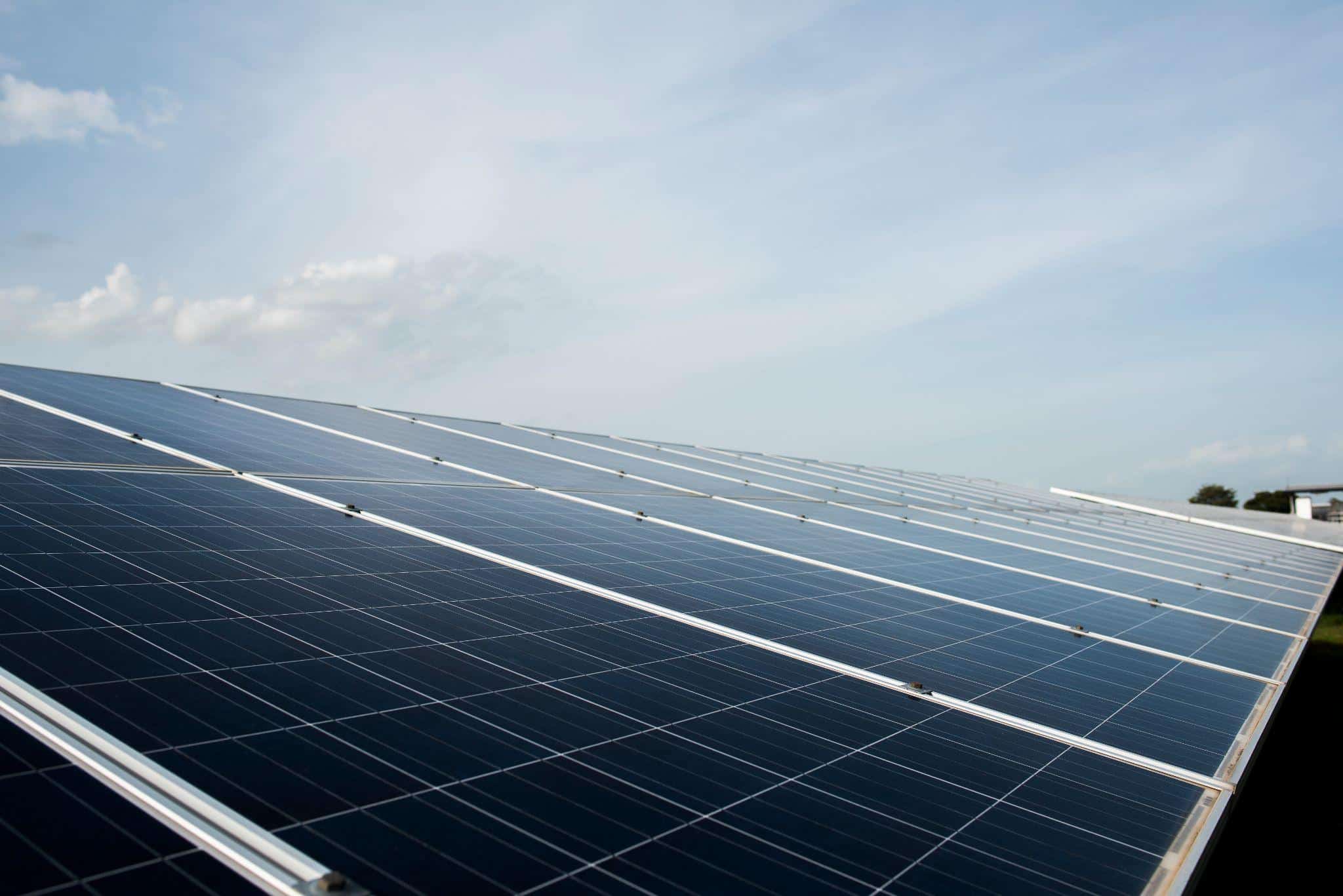 Rows of solar panels are installed outdoors under a clear sky, capturing sunlight and generating renewable energy.
